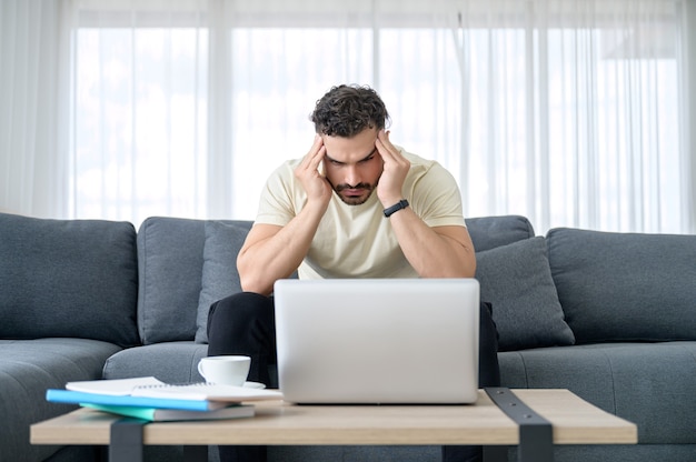 Ein Mann, der lässige Kleidung trägt, die von zu Hause aus arbeitet, Online-Besprechung, Videoanruf, Konferenz und Online-Lernen mit Stress