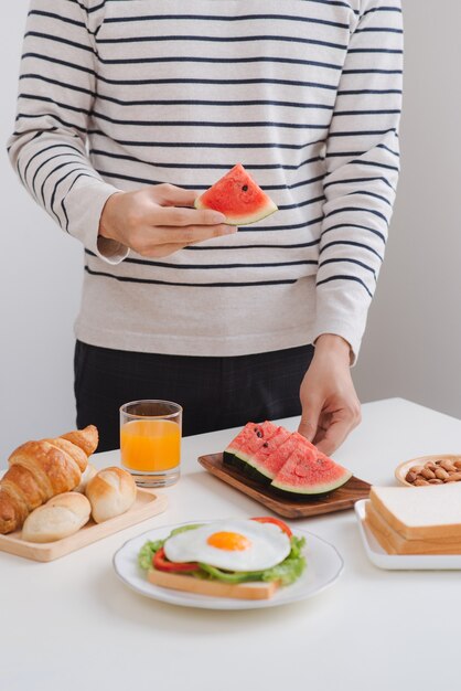 Ein Mann, der morgens zu Hause mit Sandwich und Obst frühstückt.