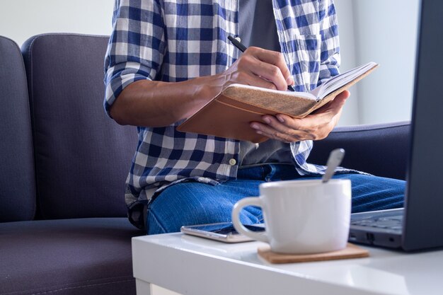 Ein Mann, der online im Wohnzimmer auf dem Sofa arbeitet oder studiert.