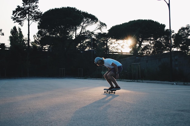Ein Mann, der während des Sonnenuntergangs auf einem Spielplatz Skateboard fährt