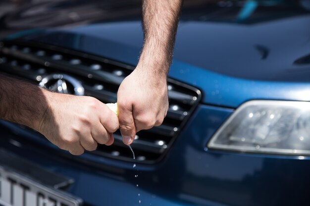 Ein Mann drückt neben dem Auto einen Lappen aus