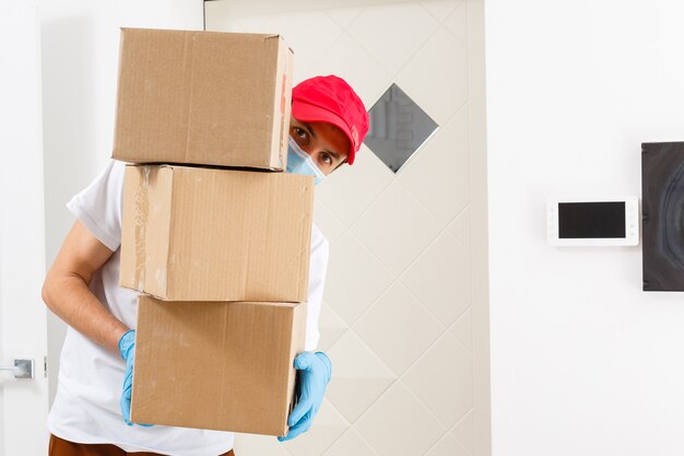 Ein mann, eine medizinische maske und blaue gummihandschuhe mit einer schachtel, ein paket in den händen. lebensmittellieferung während der quarantäne der coronavirus-pandemie. lieferung nach hause, online-bestellung. online einkaufen .