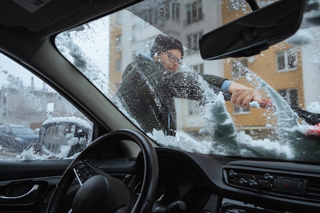 Ein Mann entfernt Schnee aus der Innenansicht seines Autos