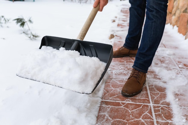 Ein Mann entfernt Schnee mit einer Schaufel vom Pfad in der Nähe des Hauses