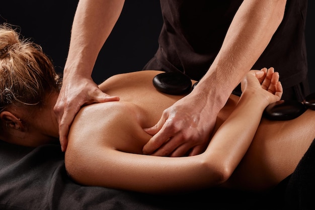 Ein Mann erhält eine heiße Stein-Massage ein Masseur gibt eine Stein-Massage