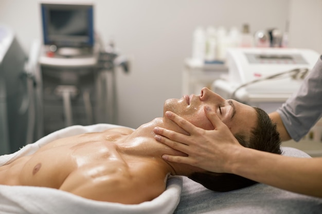 Ein Mann erhält in einem Spa-Salon eine therapeutische Massage von Körper und Gesicht