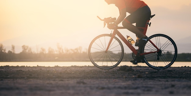 Ein Mann fährt bei Sonnenuntergang am See am Himmel Fahrrad