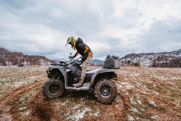 Ein Mann fährt ein ATV in der Schlammverwehung und fährt ein ATV-Quad durch Schlamm und Schnee