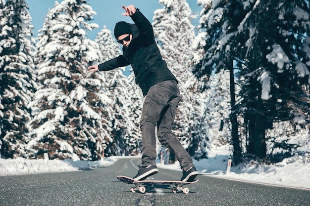 Ein Mann fährt im Winter auf der Straße Skateboard