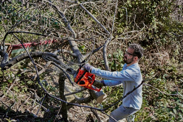 Foto ein mann fällt einen wald mit einer elektrischen kettensäge