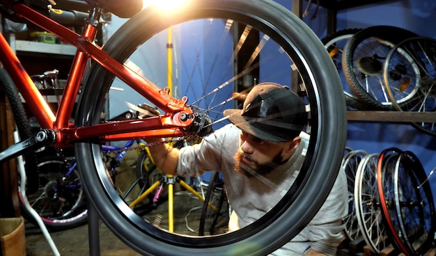 Ein Mann Fahrradmechaniker mit Bart baut in seiner Werkstatt ein Mountainbike zusammen.