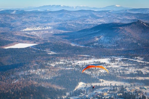 Ein mann fliegt mit einem orangefarbenen fallschirm