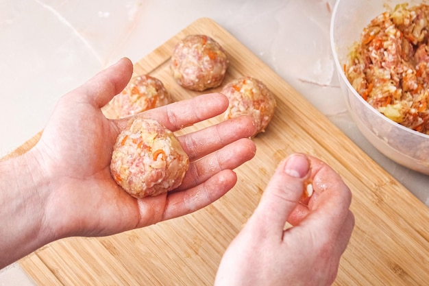 Ein Mann formt faule Kohlröllchen aus Hackfleischkohlreis, der Mann formt Fleischbällchen