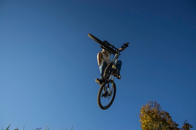 Ein Mann führt einen Stunt mit einem Fahrrad gegen einen klaren Himmel durch