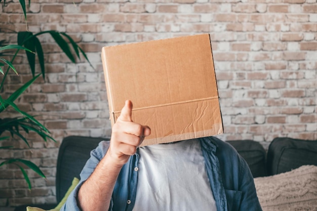 Ein Mann gesteht, während er sein Gesicht mit einer Kartonbox zu Hause bedeckt