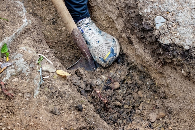 Ein Mann gräbt auf einer Baustelle einen Graben mit einer Schaufel