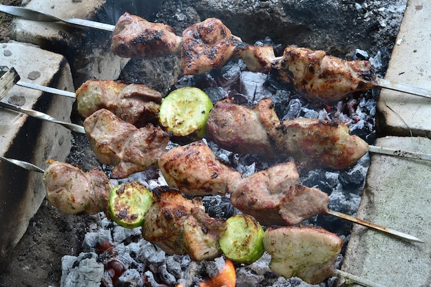 ein Mann grillt Fleisch und Gemüse auf Spitzen im Garten