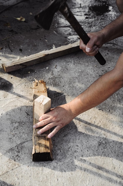 Ein Mann hackt Holz mit einer Axt, um ein Feuer anzuzünden. Hinterhofarbeit