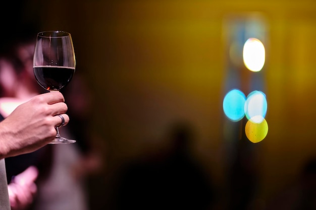 ein mann hält ein glas rotwein in der hand unscharfer hintergrund bokeh