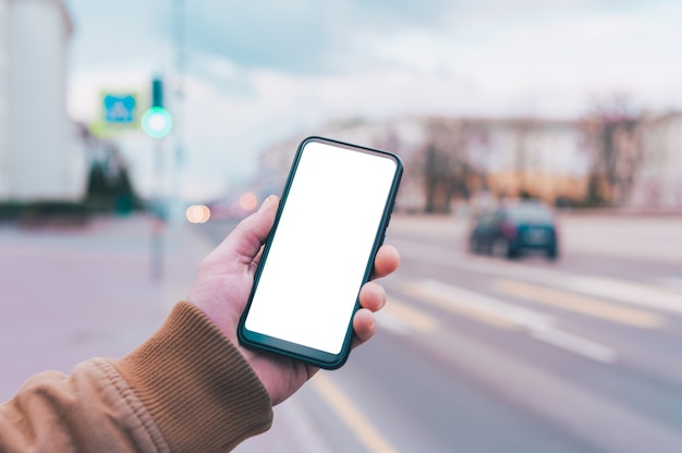 Ein Mann hält ein Modell eines Smartphones mit einem weißen Bildschirm auf dem Hintergrund der Straße.