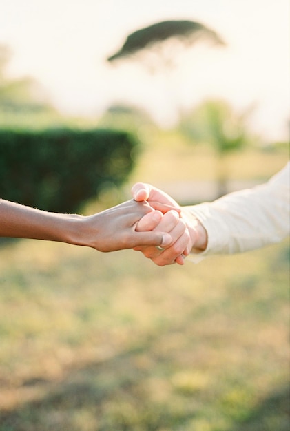 Ein Mann hält eine Frau an der Hand, während er in einem grünen, gesichtslosen Garten steht