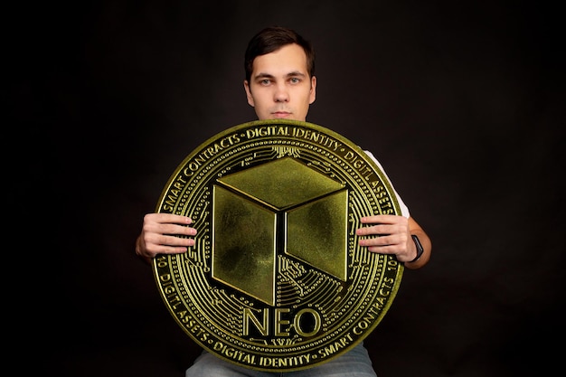 Ein Mann hält eine NEO-Münze als Symbol für Technologie in seinen Händen