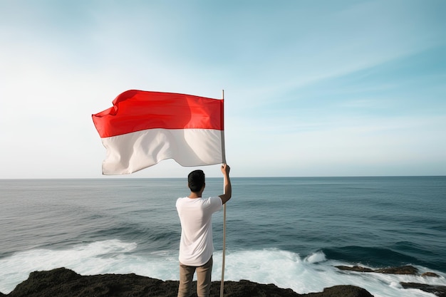 Ein Mann hält eine rot-weiße indonesische Flagge und blickt auf das Meer