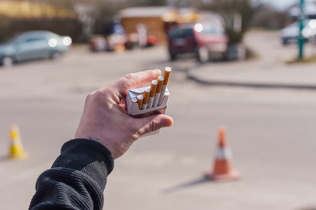 Foto ein mann hält eine schachtel zigaretten in den händen.