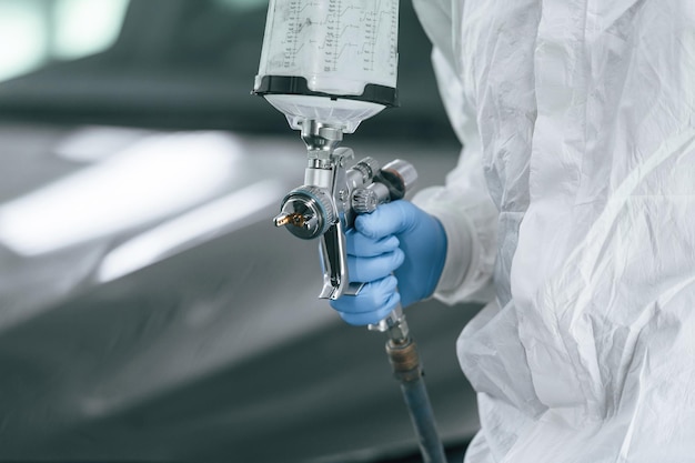 Ein Mann hält eine Sprühpistole in der Hand, um ein Auto zu malen
