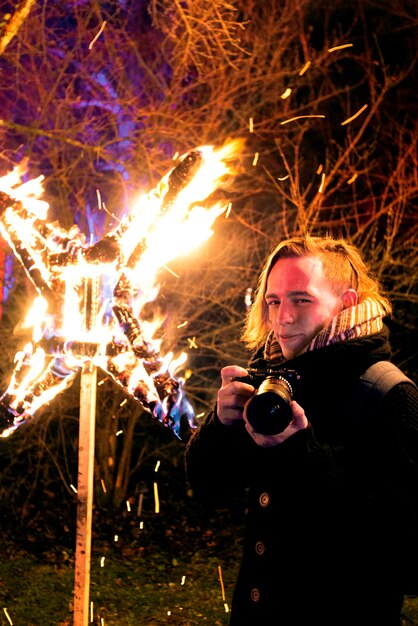 Foto ein mann hält nachts eine kamera am feuer