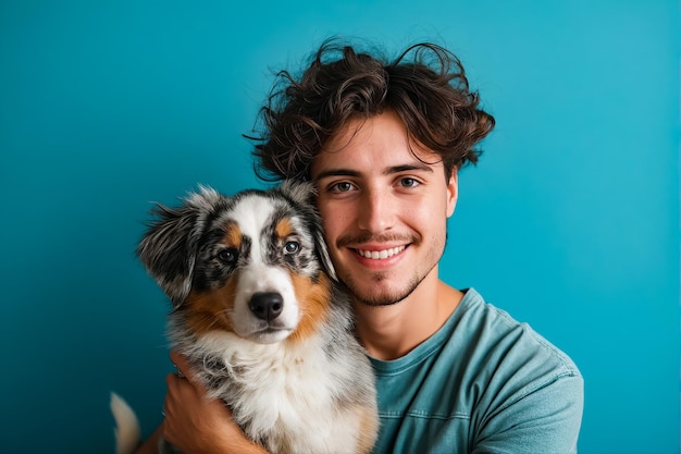 Ein Mann hält seinen Hund vor einem blauen Hintergrund