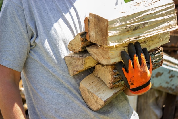 Ein Mann hält viel gehacktes Brennholz in seinen Händen