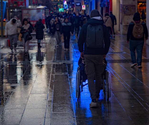 Ein Mann hilft einer behinderten Person, sich im Rollstuhl auf der Straße zu bewegen