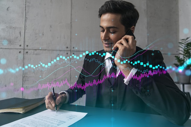 Ein Mann im Büro, der Papiere unterschreibt, während er Telefon- und Börsendiagramm und Diagrammhologramm spricht Doppelbelichtung Abendgarderobe