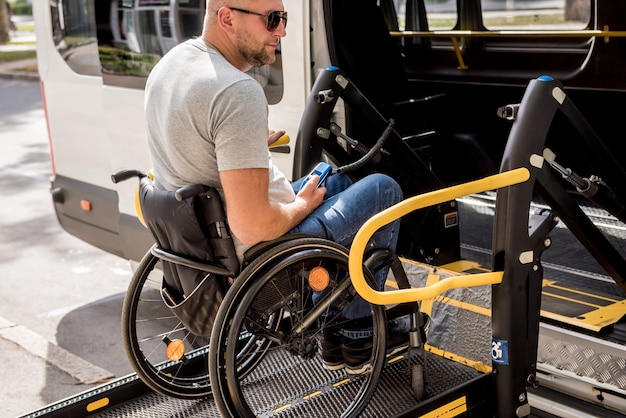 Ein Mann im Rollstuhl auf einem Aufzug eines Fahrzeugs für Menschen mit Behinderungen.