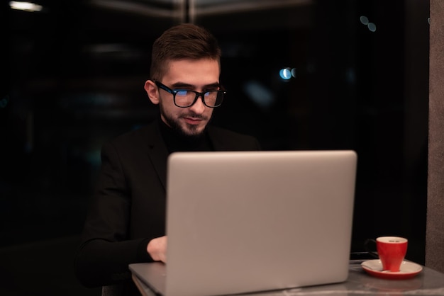 Ein Mann im schwarzen Anzug arbeitet an einem Laptop.