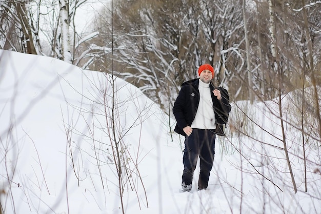 Ein Mann im Winter im Wald. Ein Tourist mit Rucksack geht im Winter durch den Wald. Winteraufstieg.