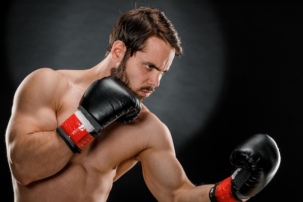 Ein Mann in Boxhandschuhen Ein Mann Boxen auf schwarzem Hintergrund Das Konzept eines gesunden Lebensstils