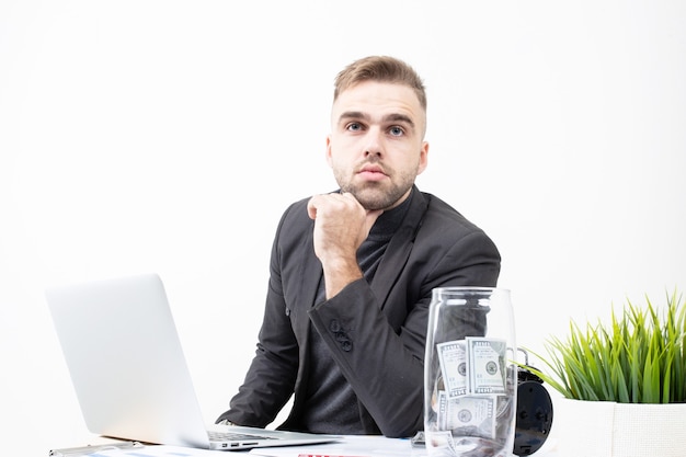 Ein Mann in Businesskleidung arbeitet an einem Laptop an einem Tisch auf weißem Hintergrund