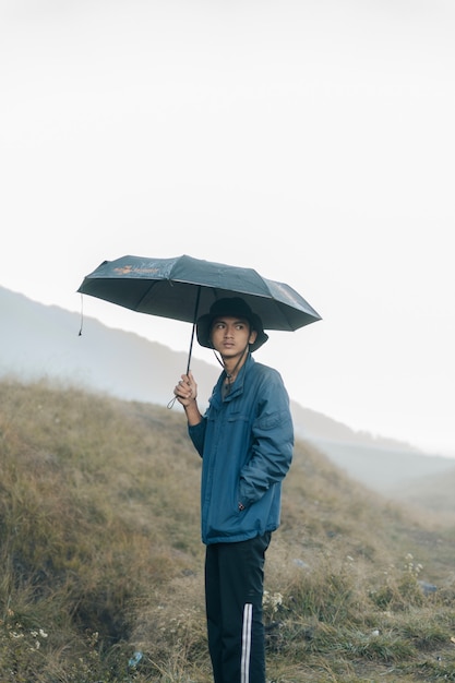 Ein Mann in den Bergen mit einem Regenschirm