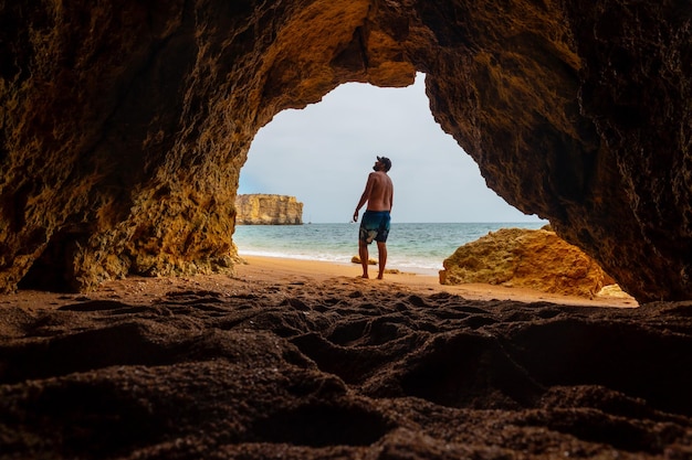 Ein Mann in der natürlichen Höhle an der Algarve im Sommer am Strand von Praia da Coelha Albufeira Portugal