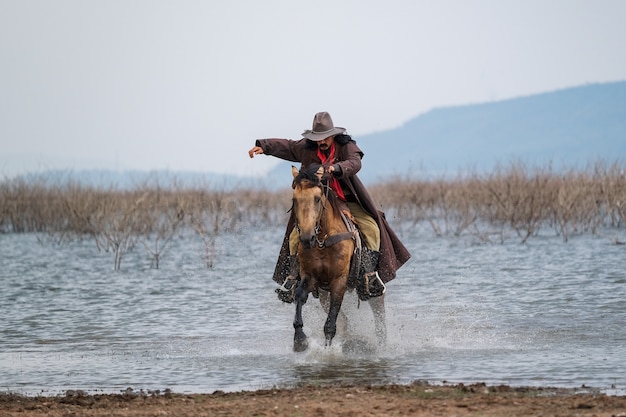 Ein Mann in einem Cowboy-Outfit mit seinem Pferd