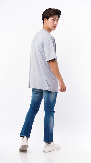 Ein Mann in einem grauen Hemd und Jeans geht auf einem weißen Hintergrund