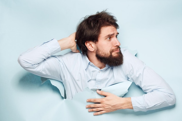 Ein Mann in einem Hemd lugt hinter der Wand seiner Karriere- und Arbeitsgefühle hervor