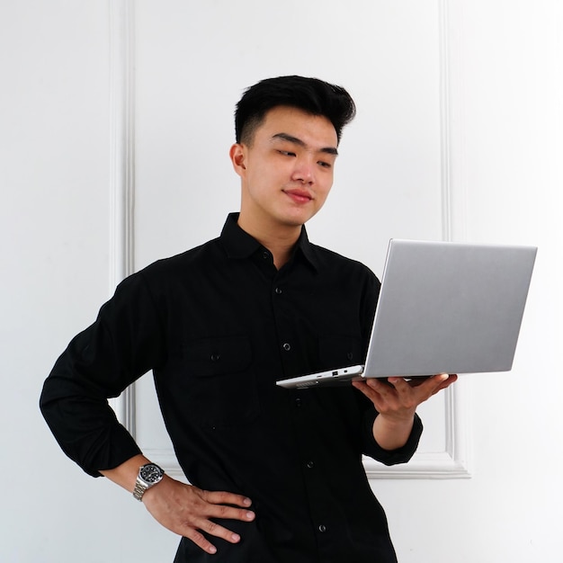 Ein Mann in einem schwarzen Hemd hält einen Laptop in der Hand.