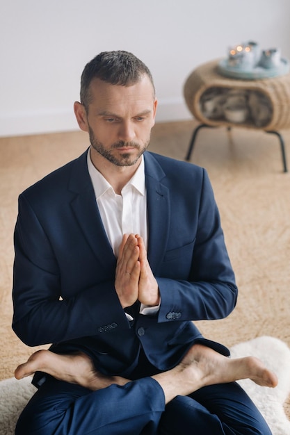 Ein Mann in einem strengen Anzug macht Yoga, während er in einem Fitnessraum sitzt