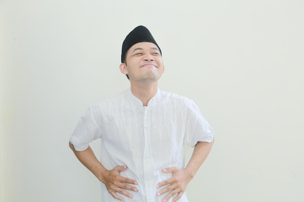 Ein Mann in einem traditionellen malaiischen Outfit lächelt und lächelt mit seinen Händen auf seinen Hüften