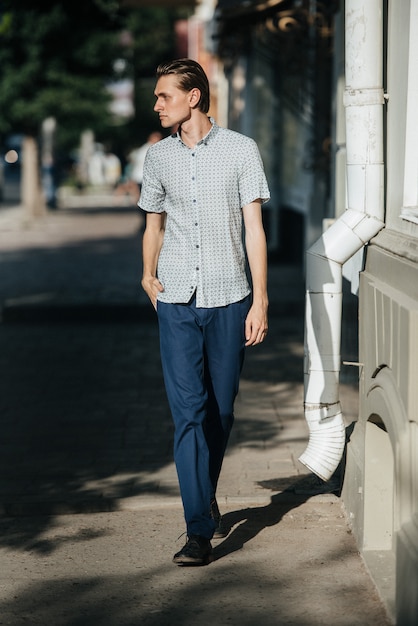 Ein Mann in einem weißen karierten Hemd und einer blauen Hose wirft für die Werbung für Herrenbekleidung auf. Dreharbeiten für Herrenbekleidungsgeschäft