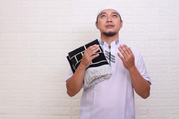 Ein Mann in einem weißen Outfit hält ein heiliges Buch und betet