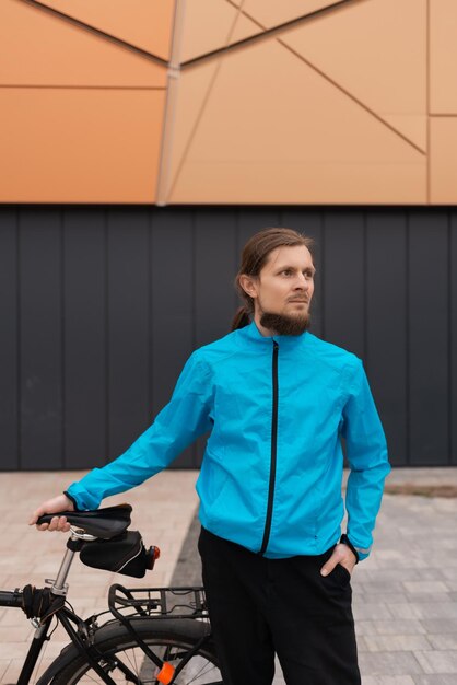 Ein Mann in einer blauen Jacke hält sein Fahrrad in der Stadt. Hochwertiges Foto